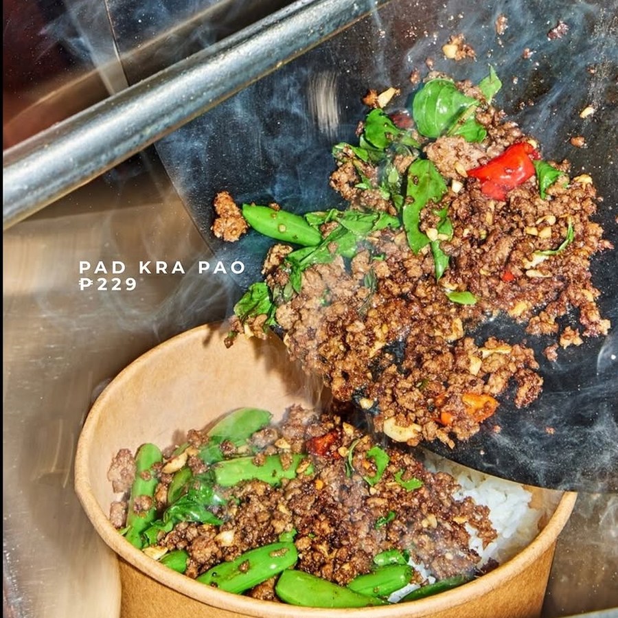 Pad Kra Pao being tipped from the wok onto rice